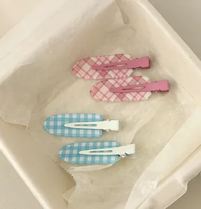 Gros plan de quatre pinces à cheveux à carreaux roses et bleues dans une boîte en bois