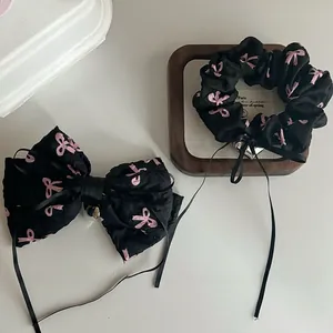 Detail of black and pink bow hair clip and scrunchie with ribbons and heart charm