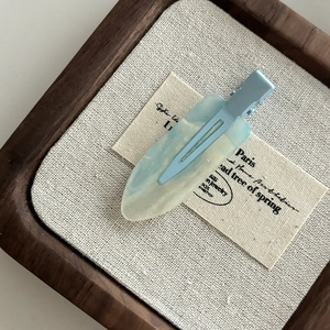 Detail of blue translucent resin hair clip with fine glitter on linen background