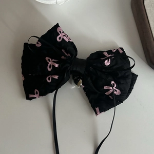 Elegant black bow hair clip with pink ribbon print and silver bell charm accessory