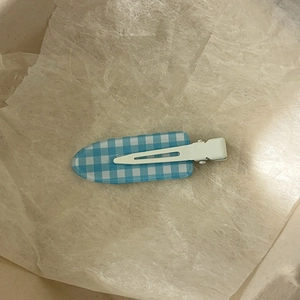 Vue détaillée d'une pince à cheveux à carreaux bleus et blancs sur papier de soie