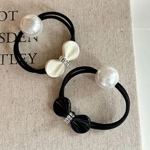 Elegant bow hair ties with white pearls and sparkling rhinestone on a textured background