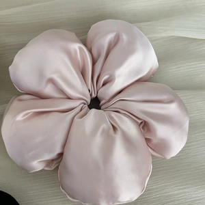 Gros plan d'un chouchou fleur géante en satin rose pastel avec un fini soyeux