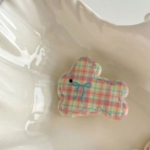 Detailed view of a cute resin rabbit hair clip with pink plaid patterns on a shell tray
