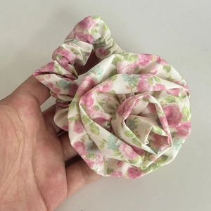 Macro detail of floral rose scrunchie with soft fabric layers and elastic texture