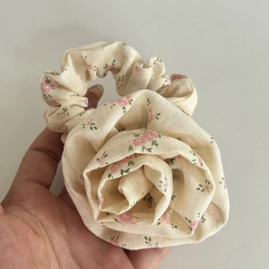 Detailed close-up of cream floral scrunchie with pink rose print held by hand