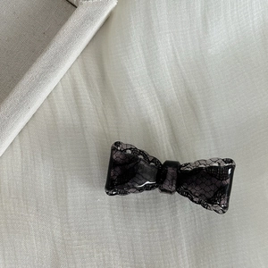 Detail view of vintage black lace texture inside a resin bow hair clip for women
