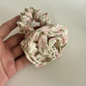 Close-up of floral fabric scrunchie with cream background and pink rose patterns
