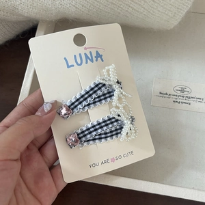 Close-up of black and white plaid hair clips with lace bows and pink heart rhinestones