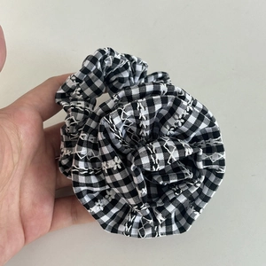 Close-up of black and white gingham hair scrunchie with delicate floral embroidery details