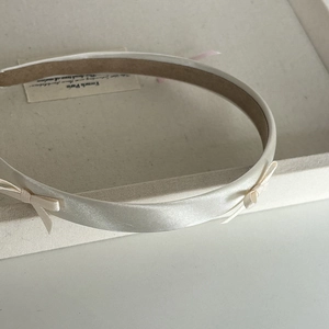 Detailed view of cream satin headband with delicate bows and non-slip velvet lining