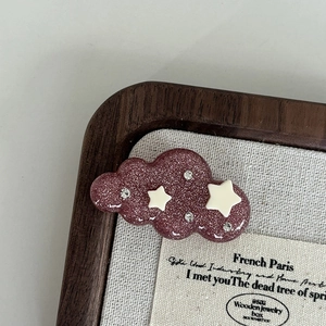 Close-up of pink glitter cloud hair clip with white stars and rhinestones on tray