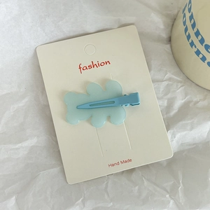 Close-up of a light blue wavy acrylic hair clip on a handmade fashion card
