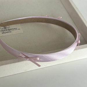 Detailed view of pink satin headband with bow showing anti-slip inner texture
