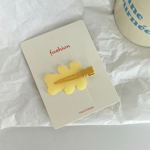 Detail view of yellow cloud-shaped resin hair clip on a handmade display card