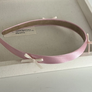 Detailed macro view of pink satin headband with delicate cream ribbon bow and anti-slip lining