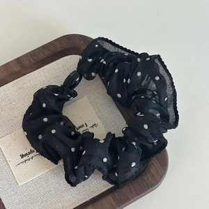 Polka dot organza hair scrunchie with a sleek black pearl slider on a wooden tray