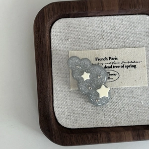 Cloud hair clip with dark grey glitter and white stars on a premium wooden tray