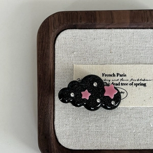 Detailed macro view of black cloud hair clip with pink stars and sparkling rhinestones