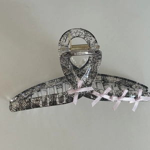 Close-up of pink lace bow hair claw clip with pearl accents and black mesh details