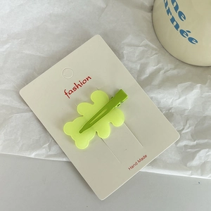 Detailed view of lime green acrylic bear hair clip on a branded handmade display card