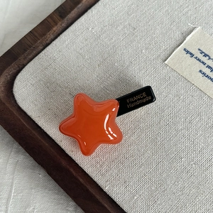 Detail of glossy orange star hair clip with France Handmade lettering on the back