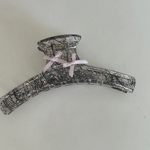 Close-up of pink ribbon bows and black lace texture on a large acrylic hair claw clip