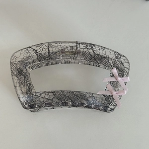 Detailed view of lace pattern claw clip with pink silk bows on a light surface