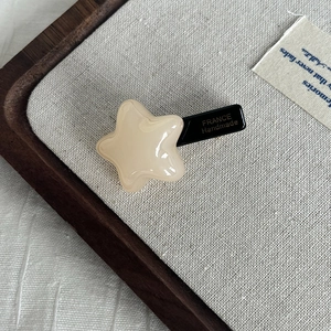 Detailed view of handmade acetate star hair clip with gold France engraving and black base