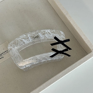Detailed view of pink lace pattern on clear acrylic hair claw with black bows