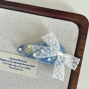 Detail of blue plaid fabric hair clip with white lace bow and faux pearl accents