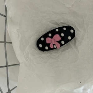Close-up of pink bow hair clip with black and white polka dots on a white background
