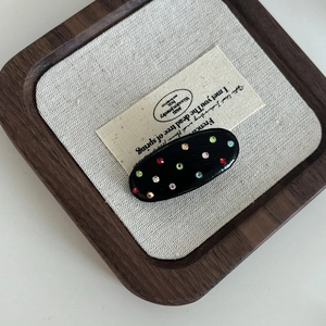 Close-up of black leather hair clip with colorful rhinestones on a vintage background