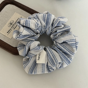 Detail of blue striped scrunchie with white lace trim and handmade fabric label