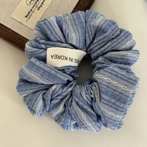 Detailed macro view of blue and white striped fabric scrunchie with woven tag