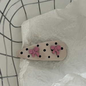 Pink bow hair clip with black polka dots on khaki base for sweet girls' styling