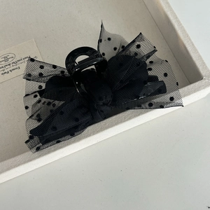 Detail of elegant black mesh bow hair claw with polka dots on a light grey tray