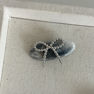 Détail de la pince à cheveux marbrée à l'encre avec nœud en perles argentées