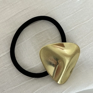 Elastisches Haargummi mit dekorativem goldenem unregelmäßigem Metalldreieck auf Stoff