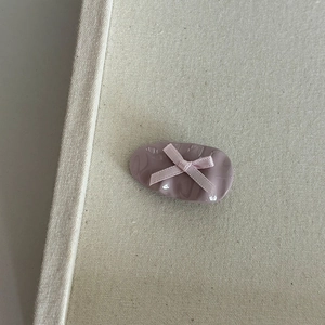 Detail of pink bow hair clip featuring a textured oval resin base and satin ribbon design