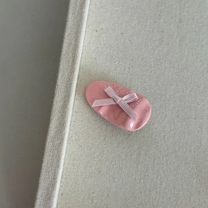 Detail view of the pink resin hair clip featuring a silk bow and embossed lettering
