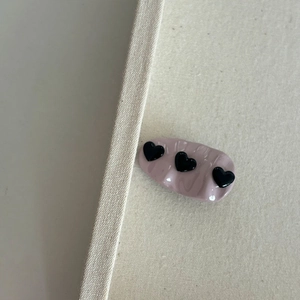 Pink heart-pattern hair clip with 3D black motifs and elegant pleated texture