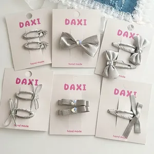 Lot de barrettes à nœuds en satin argenté avec cristaux cœur sur carte de luxe