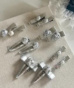 Detailed view of silver hair clips with metallic roses, pearls and heart charms