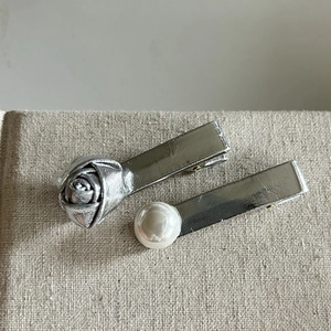 Silver flower and pearl hair clips set with metallic finish on textured fabric