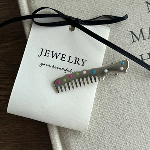 Detailed macro view of creative comb-shaped silver hair clip with colorful polka dots pattern