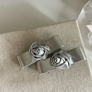 Detail of silver rose hair clips with metallic rectangle base and silk flower texture