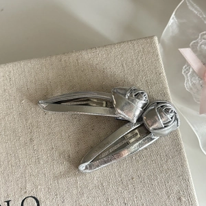Macro shot of silver leather rose hair clips with metallic texture and duckbill base