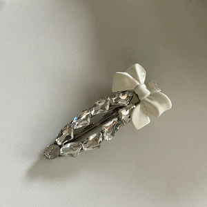 Détail de la pince à cheveux nœud argenté avec strass et pièce métallique ronde gravée