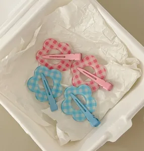 Detail view of pink and blue checkered flower hair clips with metal alligator grip back